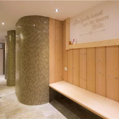 Ein ruhiger Wellnessbereich mit Holzvertäfelung und elegantem Mosaik. Eine Holzbank lädt zum Entspannen ein.
