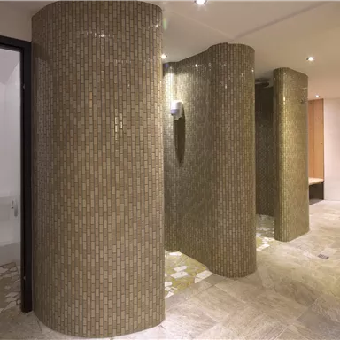 Ein eleganter Duschbereich mit runden, gefliesten Trennwänden. Der Boden ist mit hellen Fliesen gestaltet und die Beleuchtung sorgt für eine angenehme Atmosphäre.