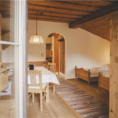 Eine gemütliche Unterkunft mit Holzmöbeln und einem großen Tisch. Der Raum hat eine einladende Atmosphäre mit einem Teppich und warmem Licht.