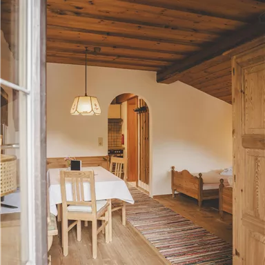 Ein gemütlicher Raum mit Holzboden und einem Esstisch. Der Raum ist freundlich beleuchtet und hat eine rustikale Atmosphäre.