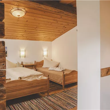 Ein gemütliches Schlafzimmer mit zwei Holzbetten und einem rustikalen Holzstrahl. Der Raum hat eine helle und einladende Atmosphäre.