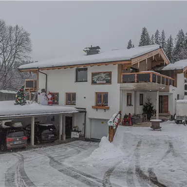 Ein schönes Haus im Schnee mit einer überdachten Garage. Die Umgebung ist winterlich und friedlich.