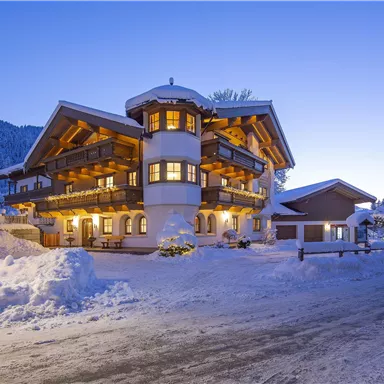 A charming chalet in the snow, surrounded by a wintry landscape. Soft lighting creates a cozy atmosphere at dusk.