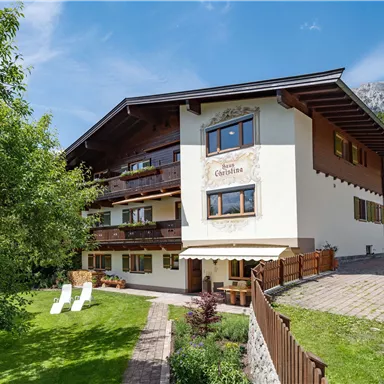 Ein charmantes Gebäude in den Bergen, umgeben von grünen Bäumen. Es gibt eine einladende Terrasse und ruhige Gartenbereiche.