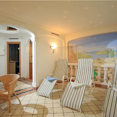 Ein entspannender Wellnessbereich mit Liegen und einer schönen Wandmalerei. Der Raum strahlt Ruhe und Komfort aus.