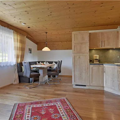 A bright apartment with a wooden beam ceiling and modern furniture. The space includes a kitchen, a dining area, and a cozy atmosphere.