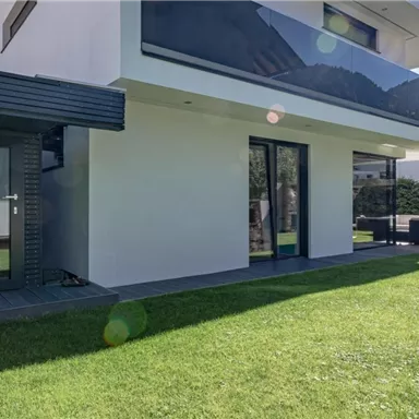 Ein modernes Haus mit einem gepflegten Garten. Die Fassade ist hell und freundlich, umgeben von einer malerischen Landschaft.