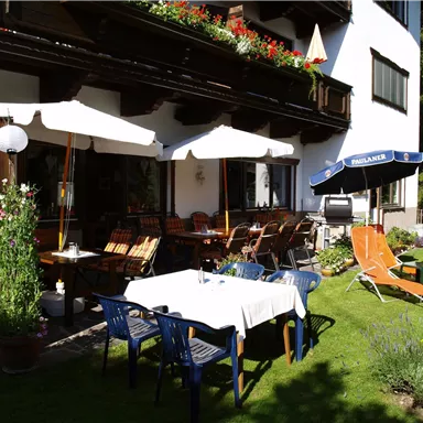 Eine gemütliche Terrasse mit Tischen und Stühlen. Sonnenschirme und Liegen laden zum Entspannen ein.