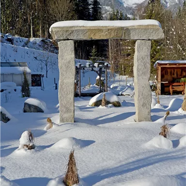 A monumental stone monument in the snow, surrounded by snow-covered landscapes. In the background, majestic mountains extend.