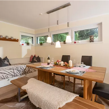 Ein einladendes Esszimmer mit einem großen Holztisch und bequemen Stühlen. Die hellen Fenster sorgen für eine freundliche Atmosphäre und viel Tageslicht.