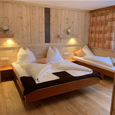 Ein gemütliches Schlafzimmer mit Holzwänden und zwei Betten. Der Raum ist gut beleuchtet und freundlich eingerichtet.