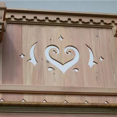 A decorative wooden panel with a heart-shaped pattern. The natural wood color and white accents create an appealing contrast.