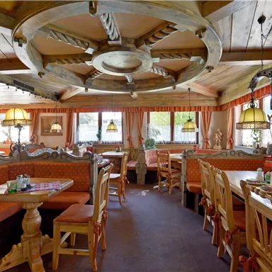 Ein gemütliches Restaurant mit Holzmöbeln und warmen Farben. Große Fenster sorgen für viel Licht und eine einladende Atmosphäre.