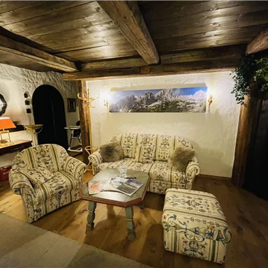 A cozy lounge with a sofa set and a side table. A picture of the mountains hangs on the wall, and the lighting creates a warm atmosphere.