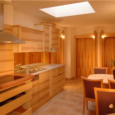A modern kitchen with wooden cabinets and a large window. A dining table with chairs invites you to linger.