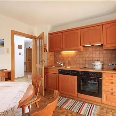 A cozy kitchen with wooden cabinets and a table. The furnishings are simple and inviting.