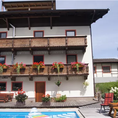 A pretty house with balconies and blooming plants. The swimming pool in the foreground invites relaxation.