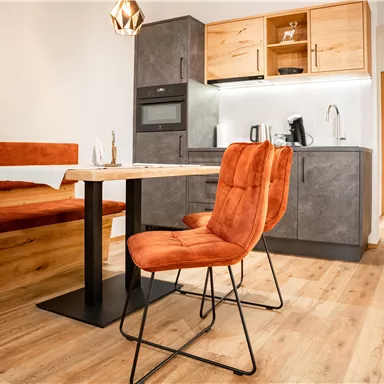 A modern kitchen with a dining table and comfortable chairs. The furnishings are made of wood and have a cozy atmosphere.