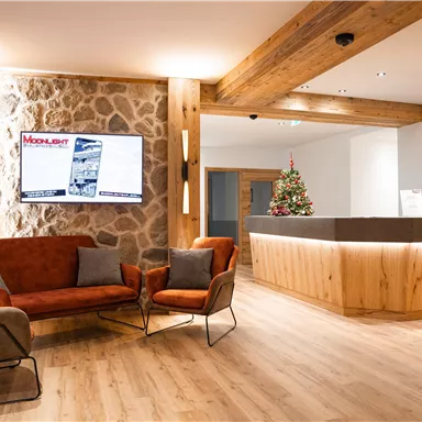 An elegant reception area with modern furniture and warm wood design. In the background, a Christmas tree is missing, which creates an inviting atmosphere.