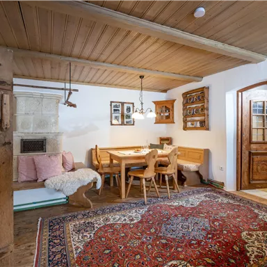 Eine gemütliche Essküche mit Holzdekor und einem großen Teppich. Der Raum ist hell und einladend, mit einem Tisch und Stühlen aus Holz.