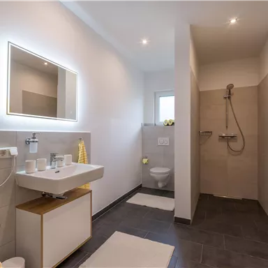 A modern bathroom with a shower and a sink. Bright walls and yellow towels create a friendly atmosphere.