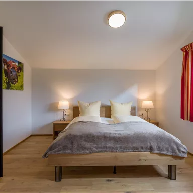 A cozy bedroom with a double bed and two nightstands. Large windows provide plenty of daylight and a pleasant atmosphere.