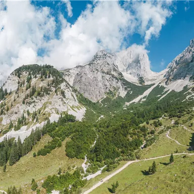 Eine beeindruckende Berglandschaft mit grünen Wiesen und hohen Gipfeln. Du könntest klare Himmel und einige Wolken sehen, die die majestätische Szene ergänzen.