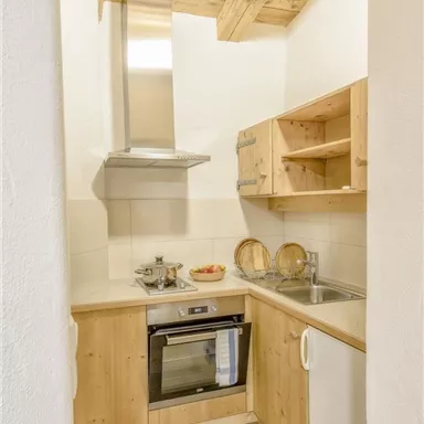 Eine moderne Küche mit Holzmöbeln und einer Dunstabzugshaube. Sie ist hell und funktional gestaltet.