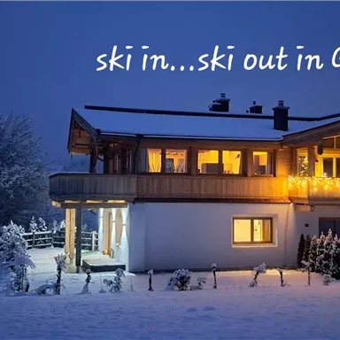 A cozy house in the snow with warm light and a beautiful setting. It stands in a winter landscape, perfect for ski enthusiasts.