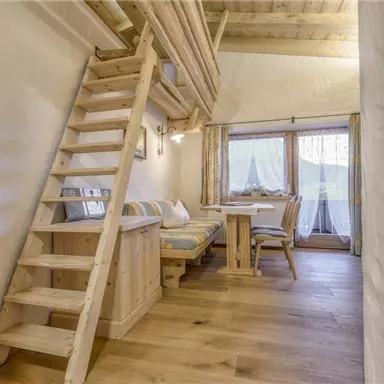 Eine gemütliche Holzwohnung mit einer Treppe und einem kleinen Essbereich. Große Fenster lassen viel Tageslicht herein.