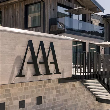 Ein modernes Gebäude mit Holz- und Steinfassade. Deutlich sichtbar ist das Logo "AAA" an der Wand.