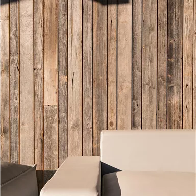 A modern living space with a bright couch and a textured wooden wall. A gray blanket is on the couch.