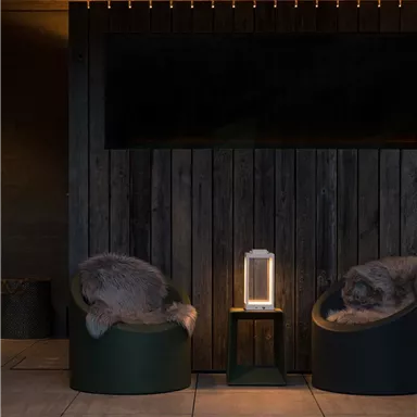 Ein stilvolles Wohnzimmer mit Holzwänden und sanfter Beleuchtung. Zwei bequeme Sessel und ein Tisch mit einer modernen Lampe schaffen eine gemütliche Atmosphäre.