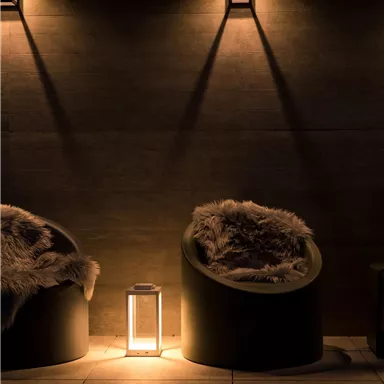 Gemütliche Sitzecken in einem dunklen Raum mit sanfter Beleuchtung. Eine Laterne sorgt für warmes Licht und schafft eine entspannte Atmosphäre.