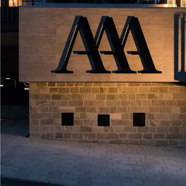 A modern building with a stylish logo in black. The exterior view is illuminated at dusk and conveys an elegant atmosphere.