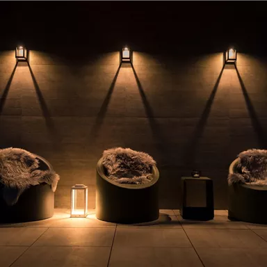 A cozy sitting area with three round armchairs and soft blankets. Gentle lighting creates a relaxed atmosphere.