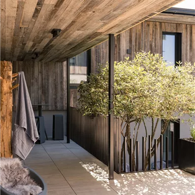 Ein moderner Balkon mit Holzverkleidung und grünen Pflanzen. Die Atmosphäre ist hell und einladend.