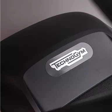 Ein schwarzes Fitnessgerät mit dem Logo von Technogym. Der Fokus liegt auf dem Detail des Geräts, das professionelles Training symbolisiert.