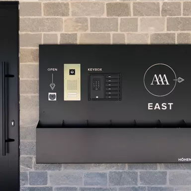 Ein modernes Eingangsbereich mit einem schwarzen Wandsystem. Es enthält einen Schlüsselkästen und ein grafisches Design mit der Aufschrift "EAST".