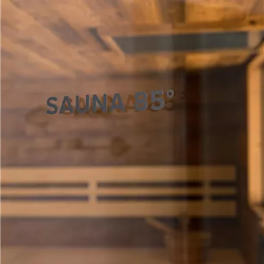 Eine Sauna mit Holzverkleidung und einer Temperaturanzeige von 85 Grad. Die Atmosphäre ist warm und einladend.