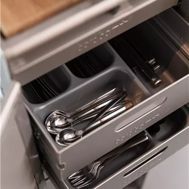 A drawer system in a modern kitchen. The drawers are well organized with cutlery and kitchen utensils.