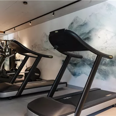 A modern gym with treadmills and other training equipment. The walls are designed with an artistic, calming graphic.
