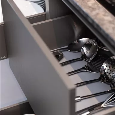 An open kitchen drawer with various cooking utensils and pots. The utensils are neatly arranged and clearly visible.