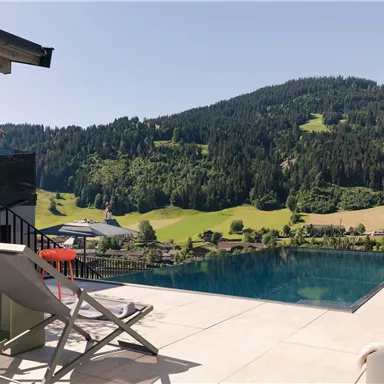 Ein wunderschöner Pool mit Blick auf grüne Hügel und Wälder. Entspannung im Freien mit modernem Design.