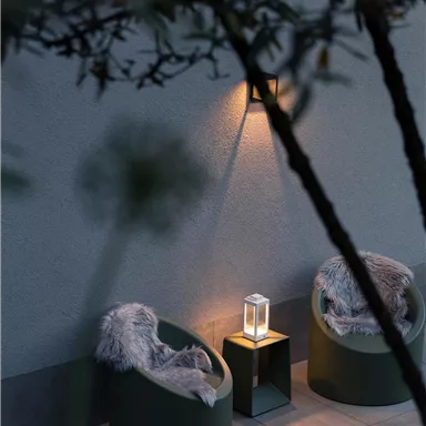 A cozy outdoor area with two modern chairs and a small lamp. Soft light creates a relaxed atmosphere.