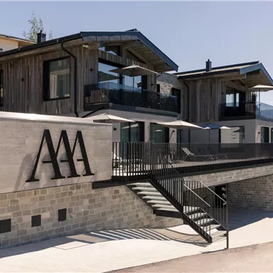 A modern building with a wooden and stone facade. It features an elegant entrance and large windows.