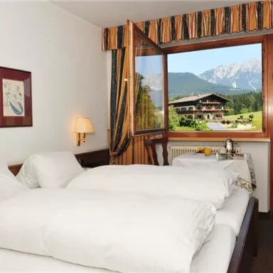 A cozy bedroom with two beds and a beautiful view of the mountains. Large windows bring in plenty of light and create an inviting atmosphere in the room.