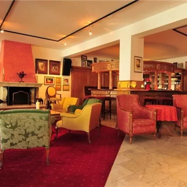 An elegant lounge with comfortable armchairs and a warm color scheme. A fireplace and decorative artworks create an inviting atmosphere.