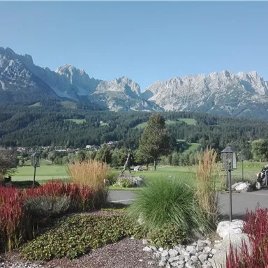 A picturesque landscape with imposing mountains in the background. Colorful flowers and well-maintained gardens create an inviting atmosphere.