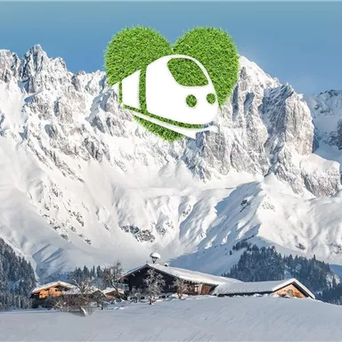 Eine atemberaubende Berglandschaft mit schneebedeckten Gipfeln. Im Vordergrund ist eine gemütliche Hütte in einer friedlichen Winterlandschaft zu sehen.